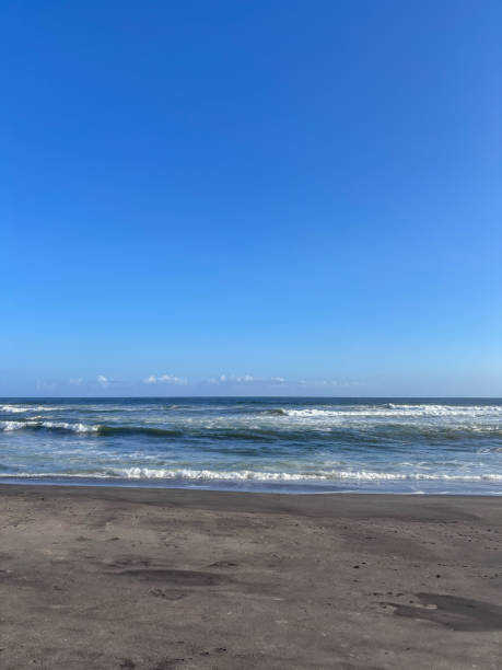 istock A beach with a clear blue sky and a few clouds. The beach is empty and the water is calm 2180714841