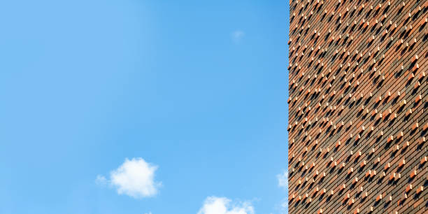 Textured wall with new brown brickwork facing against blue sky. Banner, space for text, copy space