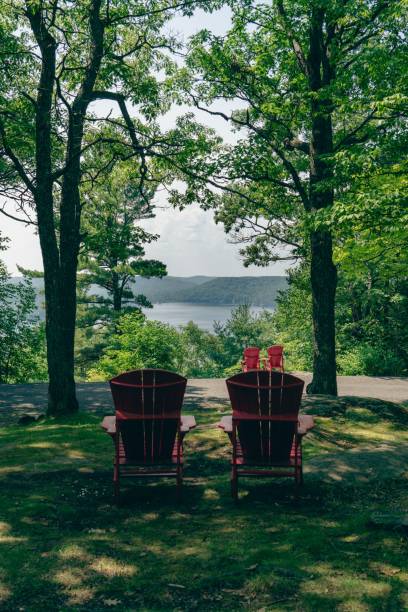 istock Red Adirondack chairs by the lake 2180718923