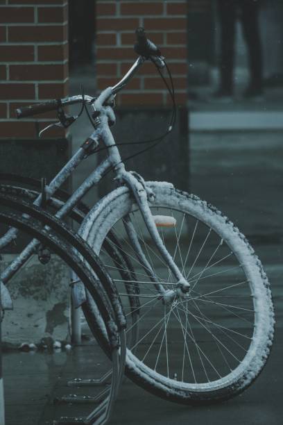 A snow-covered bicycle parked against a brick wall on a cold winter day, capturing the essence of urban life in winter.