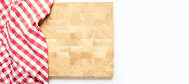 istock End grain wooden cutting board partially covered by a red and white checkered cloth, creating a cozy kitchen scene. Ideal for culinary, food preparation 2180723578