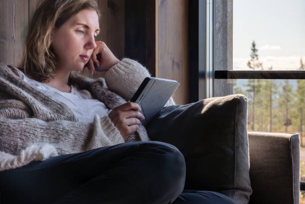 istock A Beautiful Woman Enjoying a Quiet Moment Reading an E-Reader Book in a Cabin by the Forest 2180723757