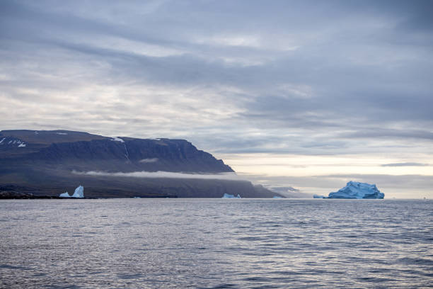 Icebergs floating in front of a mountain on Disko Island outside Ilulissiat in western Greenland