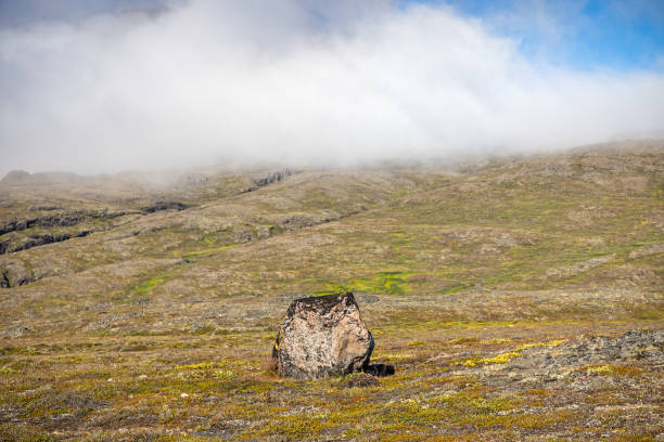 Large rock under a low cloud in the arctic landscape on Disko Island outside Ilulissiat in western Greenland