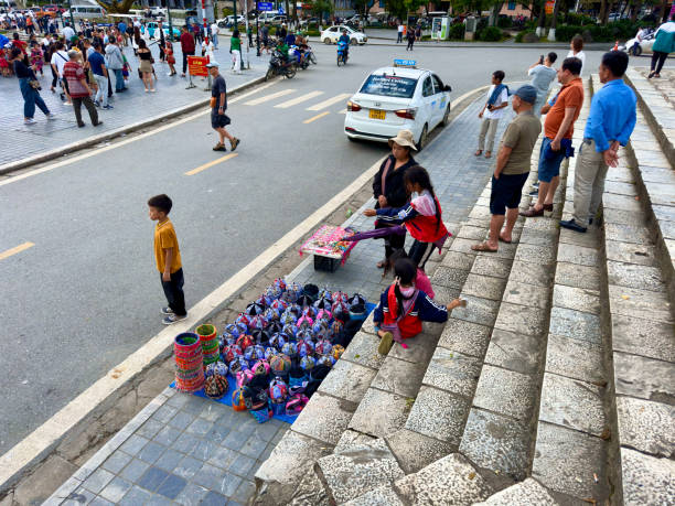 Sidewalk stalls selling souvenirs in Sapa with colorful brocade hats, shirts and pants. The vendors are ethnic people. Outside the Sapa stone church, Sa Pa Town, Lao Cai, Vietnam August 25, 2024