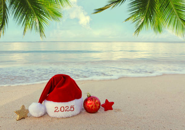 istock New Year 2025 background with red Santa hat on Caribbean beach. 2180732262
