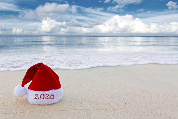 istock New Year 2025 background with red Santa hat on Caribbean beach. 2180732296