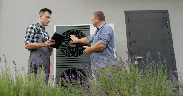 istock A technician consults with a homeowner at an external heat pump unit, discussing maintenance details. 2180737389