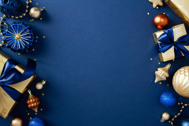 istock Christmas frame. Xmas or New Year greeting card template with gold ornaments, gift boxes, confetti on dark blue background 2180737643