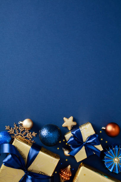 istock Modern Christmas vertical banner with luxury gold decorations, gift boxes, stars, sparkle confetti on dark blue background. Happy New Year greeting card template, poster template. Flat lay, top view 2180737835
