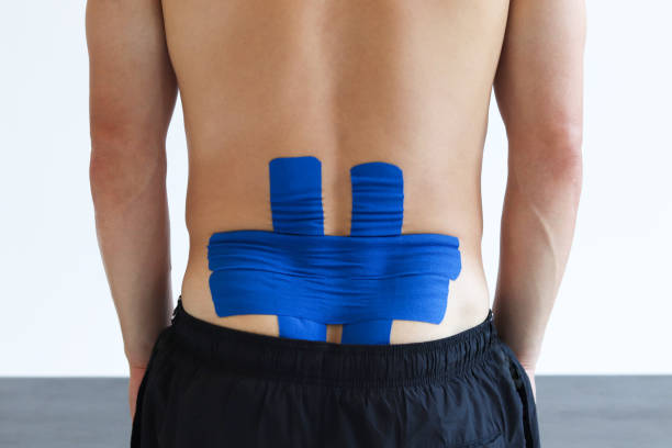 istock Physical therapist applying kinesio tape on male patient's lower back. 2180747763