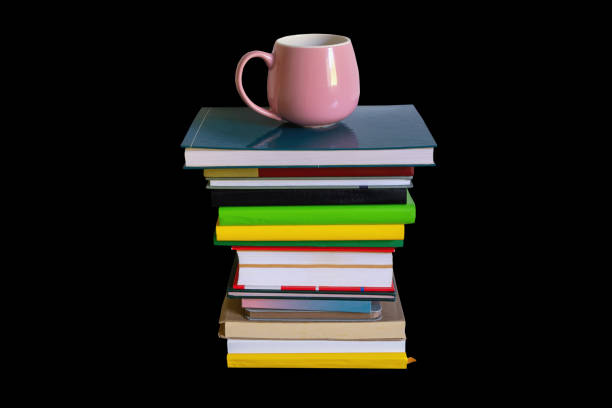 stack of books with cup of coffee on top, isolated on dark grey background