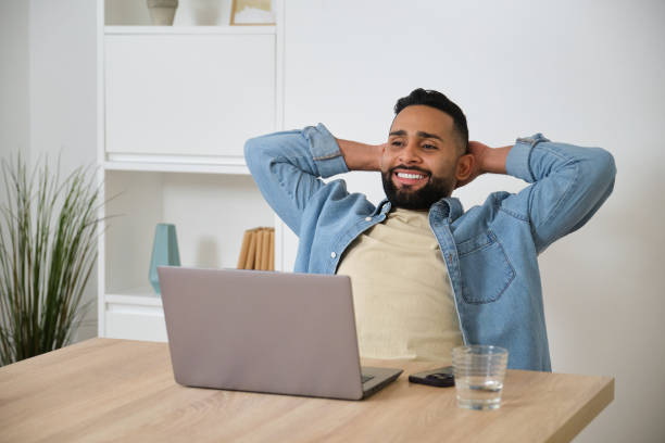 istock Happy businessman relaxing with hands behind head at workplace 2180750374
