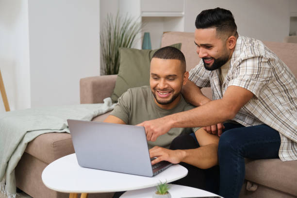 istock Two men browsing internet on laptop at home on sofa 2180750496