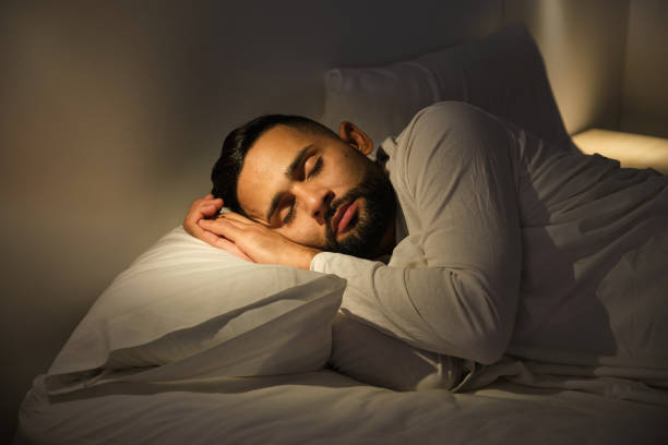 istock Young man sleeping peacefully in bed at night 2180750579