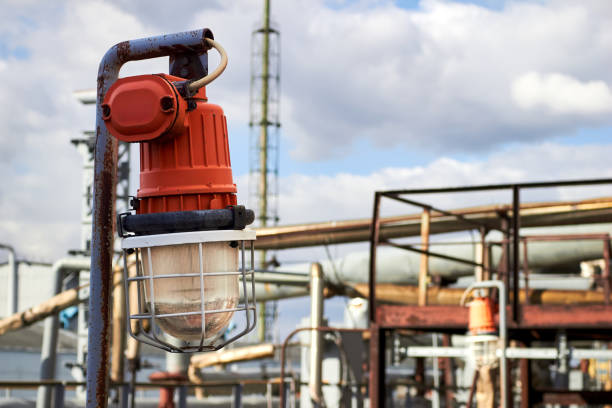 Lighting masts with lanterns in explosion-proof and fire-proof design, close-up over background of pipelines buildings and equipment of chemical plant with copy space