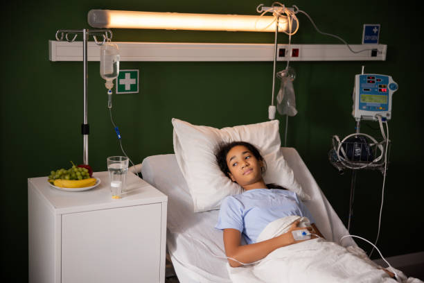 istock Daughter looking sadly out the hospital window from her bed 2180753371