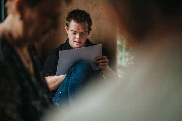 Young man with Down syndrome reading a document at home.