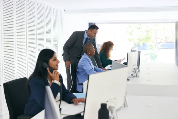 istock As the manager walks from table to table, he discusses various matters with the office workers in the corporate space. 2180757541