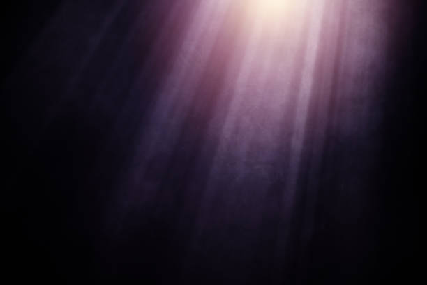 A cloud of purple smoke swirls elegantly against a dark black background, highlighted by radiant beams of light. The soft, ethereal glow of the smoke creates a mysterious and atmospheric effect.