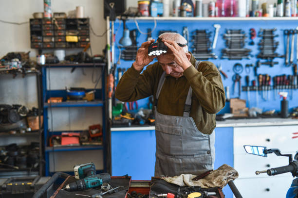 istock Working Mechanic Senior Positioning Light Equipment on Forehead Wearing Workwear in His Small Workshop 2180761359