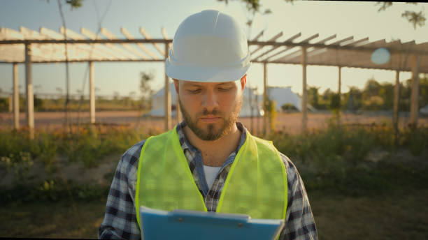 istock Close up portrait thoughtful serious Caucasian male engineer builder man guy controller helmet uniform hold checking tablet notebook looking camera outdoors countryside. Ecology industrial engineering 2180772466