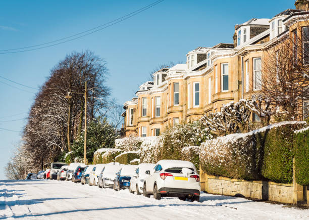 Snow covering the road and parked cars on a street of terraced houses in Glasgow's Southside.