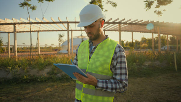 istock Focused Caucasian man businessman architect male guy engineer hardhat uniform pointing finger showing gesture park checking inspect project writing clipboard looking around construction village meadow 2180783208