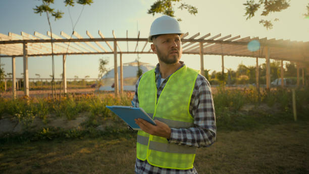 istock Focused Caucasian man businessman architect male guy engineer hardhat uniform pointing finger showing gesture park checking inspect project writing clipboard looking around construction village meadow 2180788950