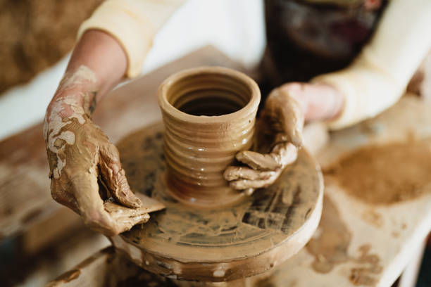 istock Muddy hands shaping a clay pot on a pottery wheel 2180791480