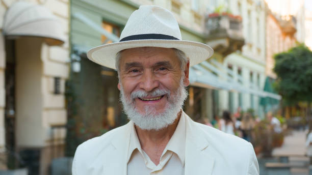 Smiling happy laughing old senior guy elderly mature grey-haired Caucasian elegant businessman male man tourist traveler looking at camera positive expression outside city street holidays retirement. High quality photo