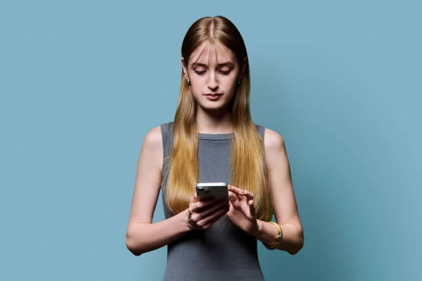 istock Young beautiful woman using smartphone on blue studio background 2180799225