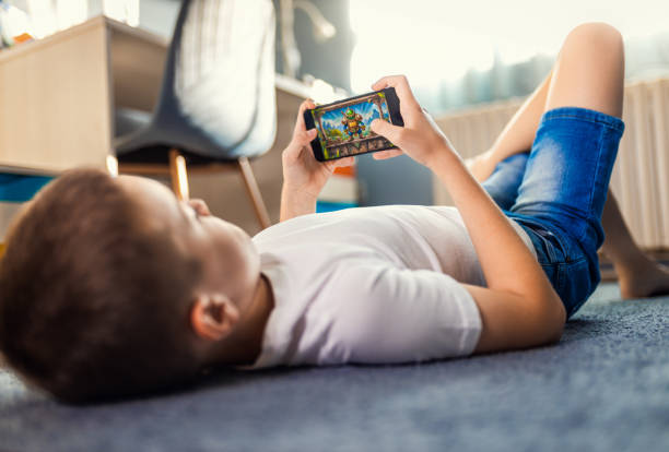 istock Boy playing video game on smartphone laying on floor in his room. 2180802365