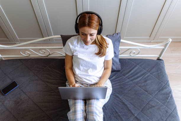 istock High angle view of a woman in bed using a laptop 2180803186