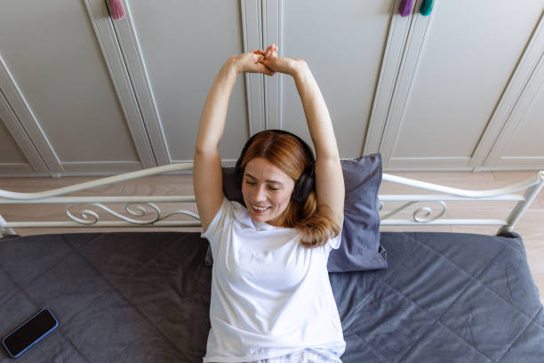 istock Young woman relaxing on bed with headphones on 2180803203