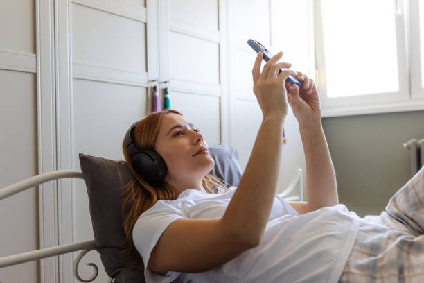 istock Woman relaxing in bed and using phone 2180803207