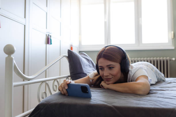 istock Young woman relaxing in bed and browsing smartphone in bed 2180803224