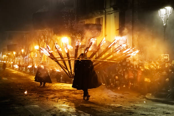 Agnone, Molise (Italy): men in traditional black cloaks and hats carry flaming torches during the ancient Christmas event called 'Ndocciata, celebrated in Agnone, city in the Molise region of Southern Italy. In this religious celebration, a great number of “‘ndocce” (torches) are carried in a typical fan shape along the main town road. The carriers start with only one torch, then bring each up to 24 fires, each about four metres high. The celebration ends with a bonfire in the town square.