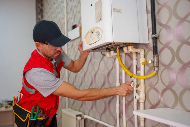istock A technician in a red vest and hat carefully works on the internal components of a wall-mounted boiler. . 2180809106