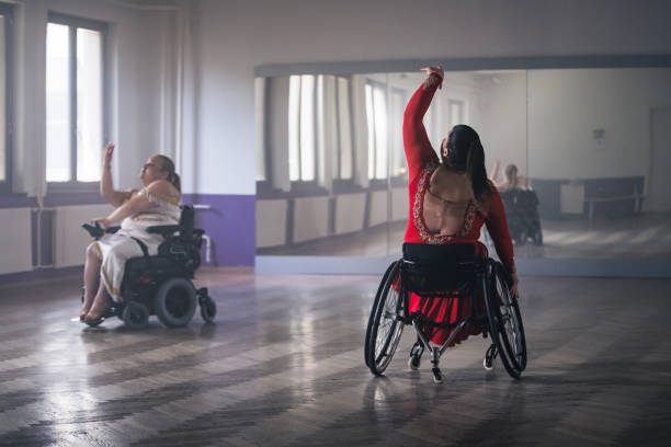 istock Wheelchair dance, two women with disability practicing movements in a ballroom 2180810211