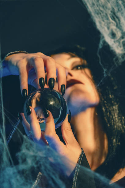 A charming witch in black dressing  holds  a lantern in the forest on the Halloween night