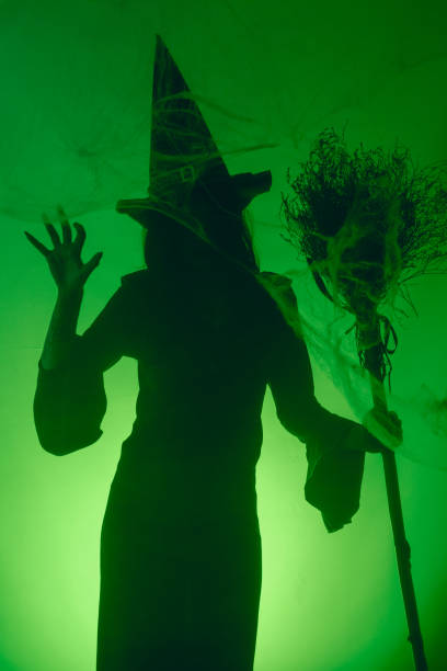 istock Witch Silhouette with Broom on Green Background 2180814369