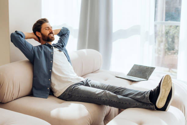 Smiling, happy Hispanic woman lying on comfortable sofa at home, relaxing after work at home