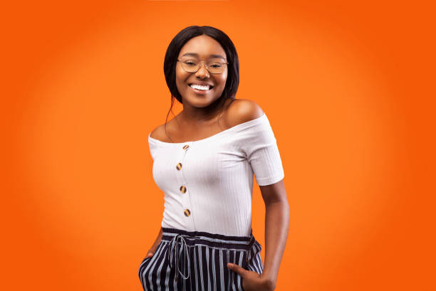 istock Happy Black Millennial Girl Standing With Hands In Pockets, Studio 2180816179