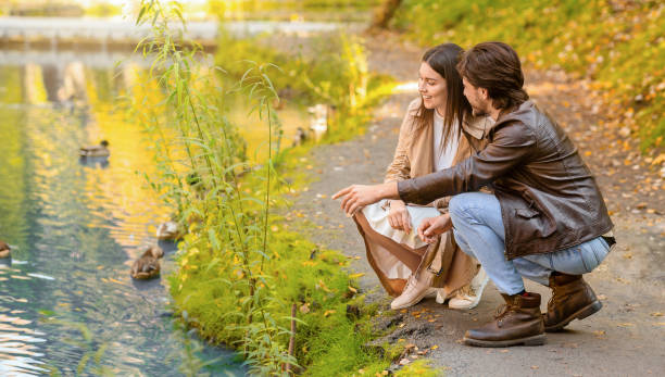 istock Joyful young couple feeding birds at park 2180817757