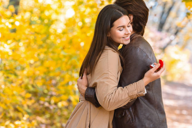 istock Woman looking at proposal ring while hugging her boyfriend 2180817809