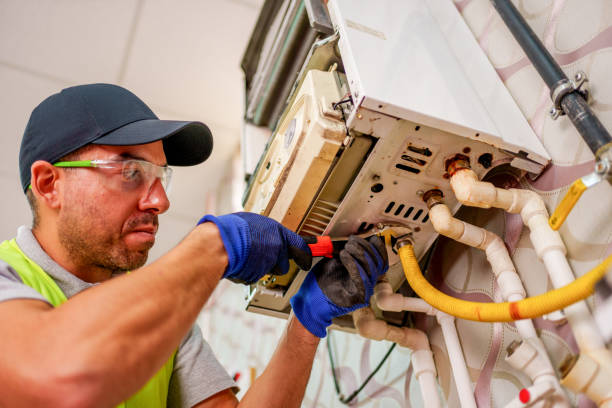 istock A technician in a red vest and hat carefully works on the internal components of a wall-mounted boiler. . 2180819310