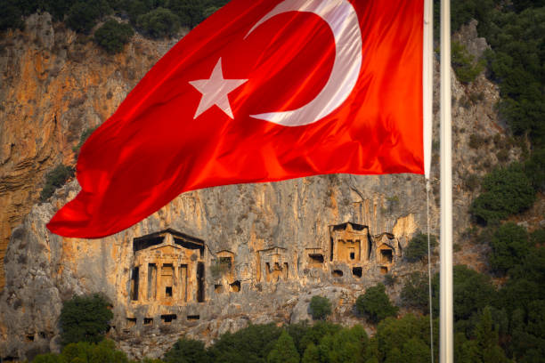 Dalyan district and Lycian rock tombs and Turkish flag. Dalyan is a natural wonder and holiday resort in the Ortaca district of Muğla province.