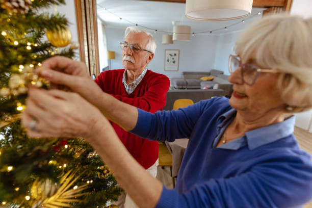 istock Senior couple joyfully decorating Christmas tree at home 2180826232