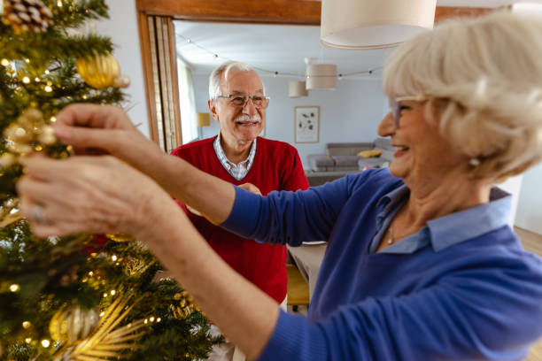 istock Senior couple joyfully decorating Christmas tree at home 2180826317